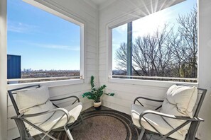 Una sala de estar con sol, dos sillones, una mesita y una planta en maceta.