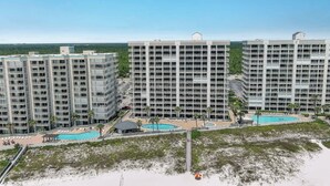 Un hotel moderno de gran altura con varios balcones, una zona de piscina y vistas a la playa.