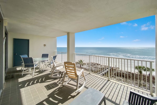 A balcony with a view of the ocean, a door, and a table with chairs.