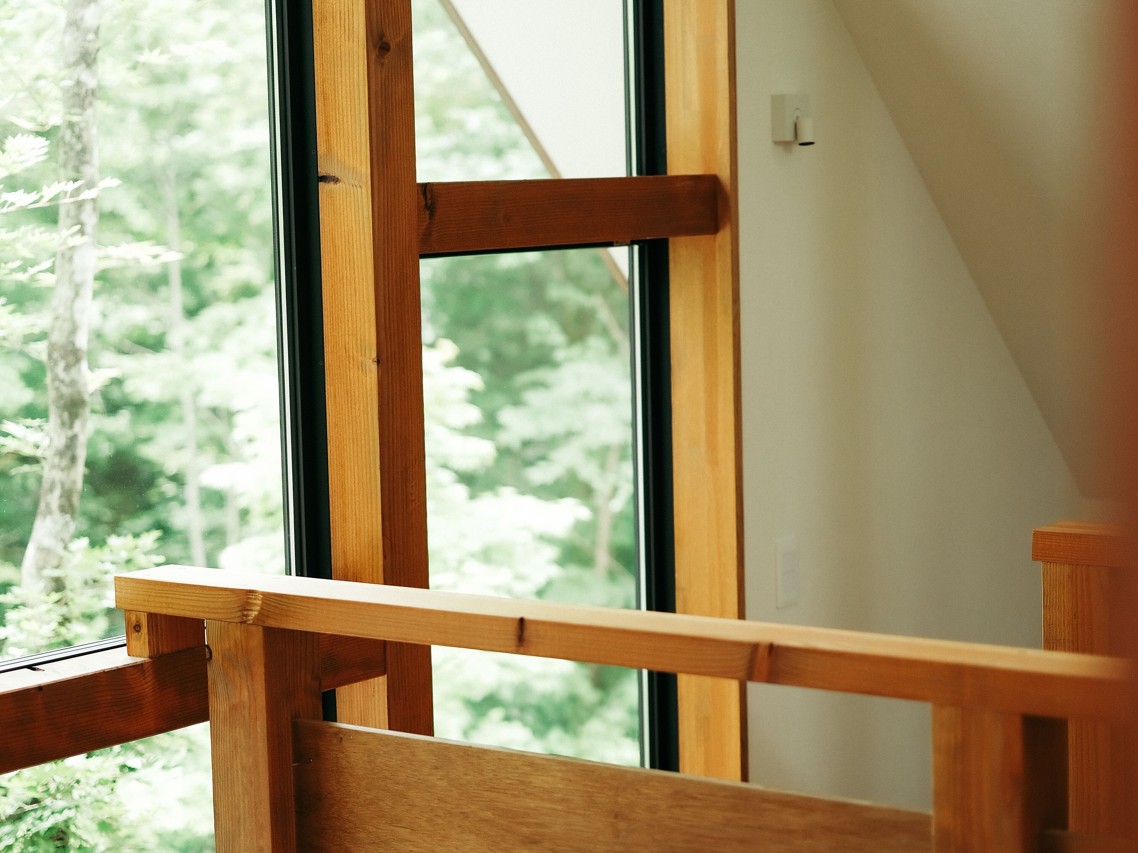 Una escalera de madera que lleva a un ventanal con vista a árboles.