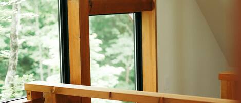 Una escalera de madera que lleva a un ventanal con vista a árboles.