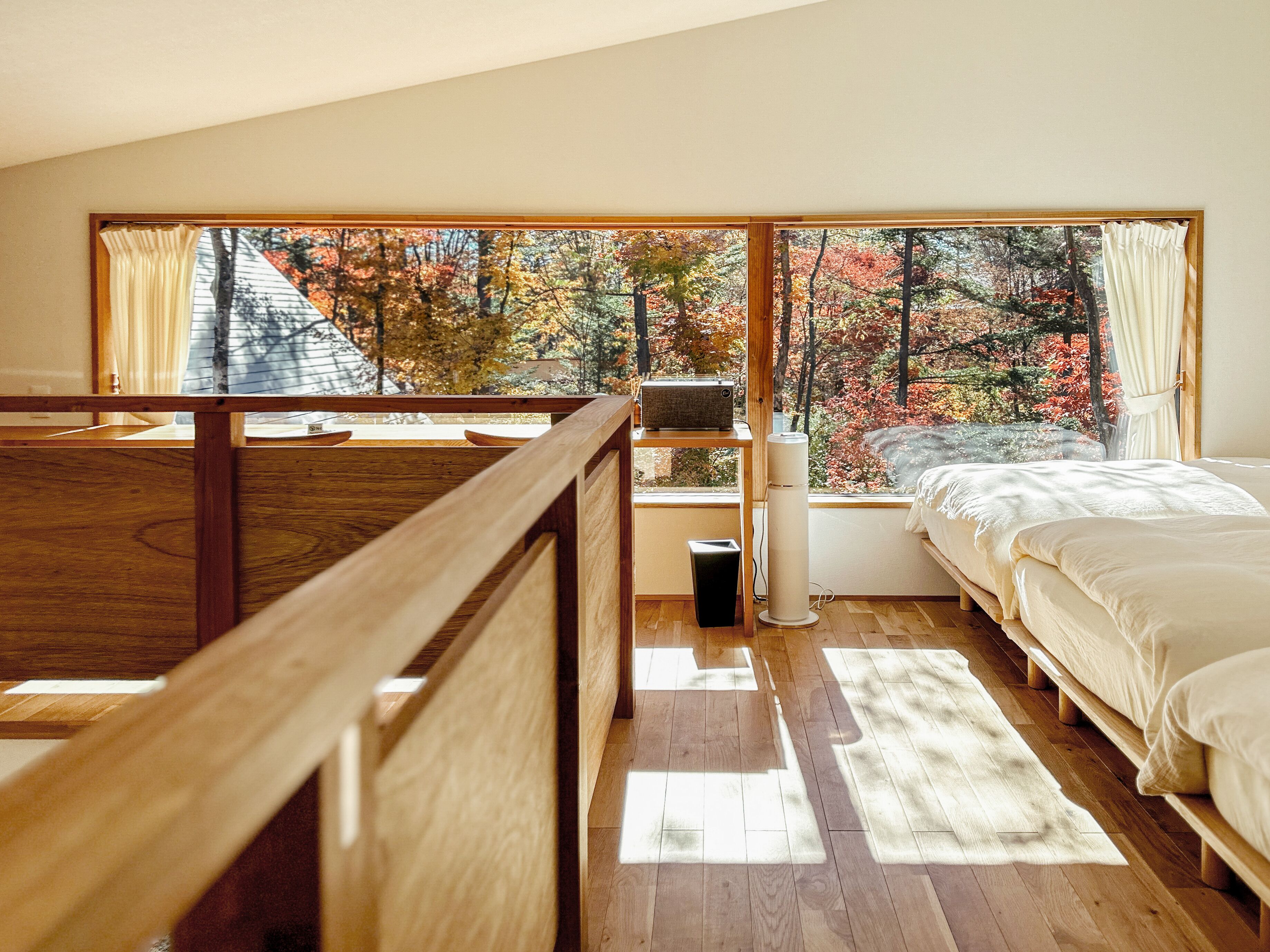 A bedroom with a large window, a bed, a bedside table, and a radiator.