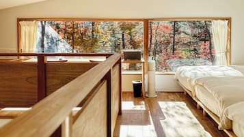 A bedroom with a large window, a bed, a bedside table, and a radiator.
