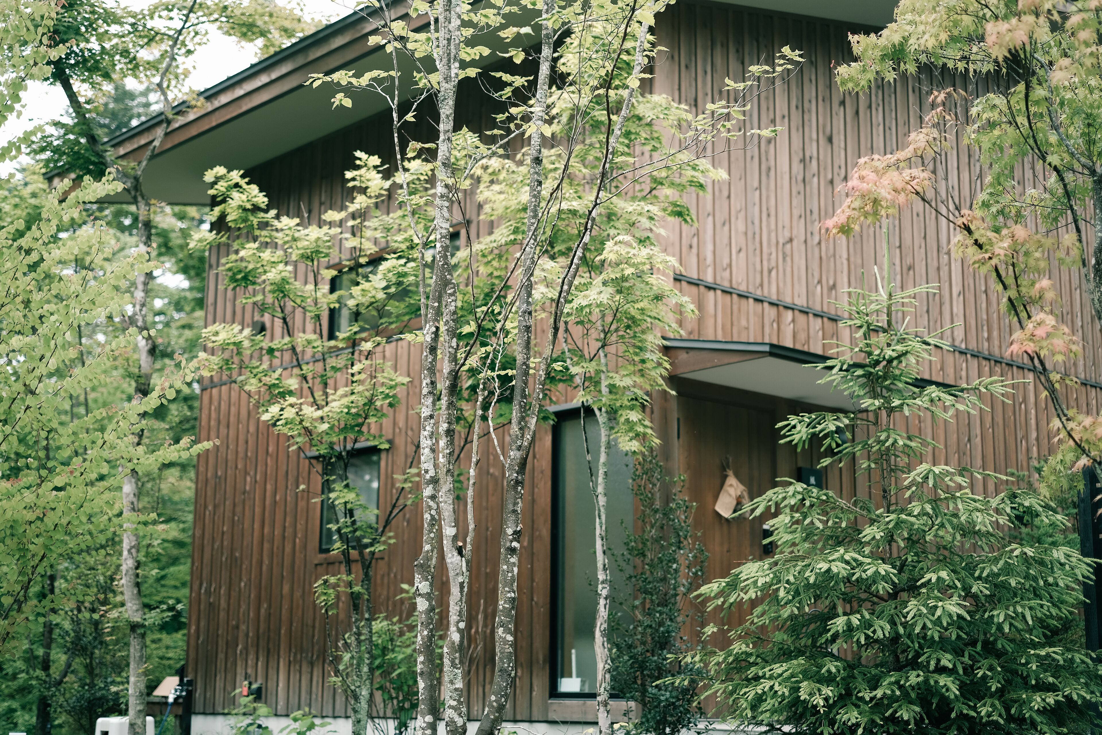 Un bâtiment moderne en bois, doté de nombreuses fenêtres et d’une porte bien visible.