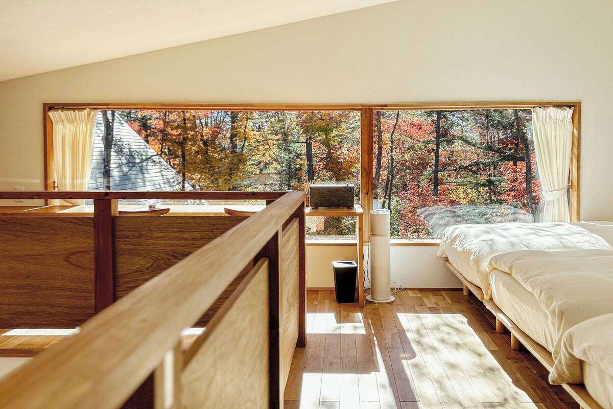 A bedroom with a large window, a bed, a bedside table, and a radiator.