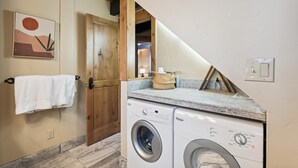 Une buanderie équipée d’un lave-linge, d’un porte-serviettes et d’une porte en bois.