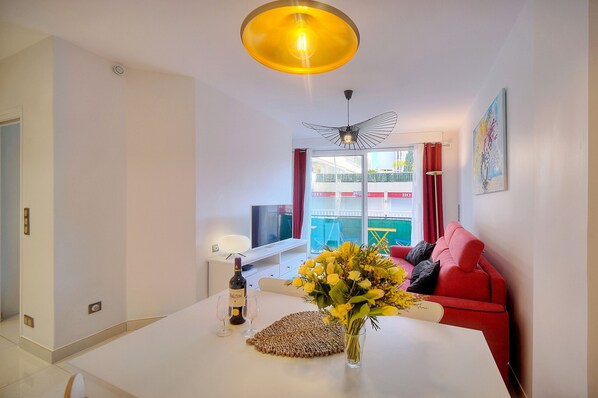 A modern living room with a white table, red sofa, and a large window with curtains. - 2 PIECES MODERNE  300 m plages Croisette A1B238 (Cannes)