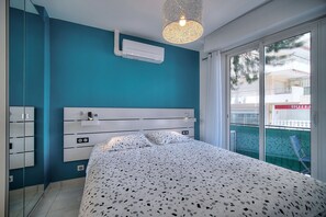 A bedroom with a bed, a bedside table, a mirror, and a window with a view of a hotel building. - 2 PIECES MODERNE  300 m plages Croisette A1B238 (Cannes)