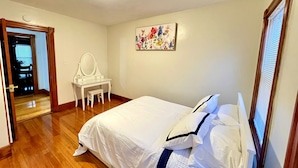 A bedroom with a bed, a desk with a mirror, and a floral painting on the wall. - Hidden Gem right in the city of Boston! (Boston)