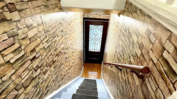 A staircase with stone walls and a wooden floor, leading to a door with a decorative glass panel. - Hidden Gem right in the city of Boston! (Boston)