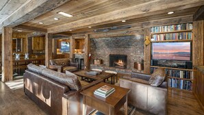 A cozy living room with a fireplace, leather sofas, wooden tables, and a bookshelf filled with books. - Rivendell - Escape at Historic Home in Olympic Valley, Near Village, Golf, and Minutes to Tahoe (Olympic Valley)