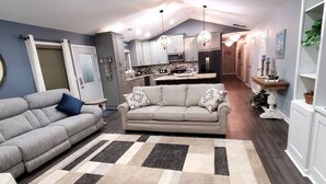 Ein modernes Wohnzimmer mit einer Couch, einem Teppich und einer Küche im Hintergrund.
