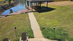 Ein Garten mit Feuerstelle, Sitzgelegenheiten im Freien, einem Steg und einem Pavillon am See.