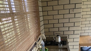 A kitchen with a granite countertop, a stainless steel sink, a green dish rack, a bottle of hand soap, and a kettle. - Haras Trevo de Ferro (Torres)
