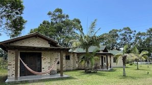A small, single-story building with a brick exterior and a tiled roof. There is a hammock tied to a wooden post in front of the building. - Haras Trevo de Ferro (Torres)