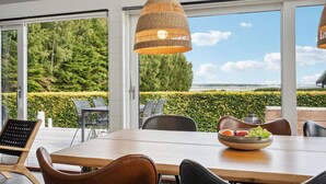 A dining area with a large table, chairs, and a hanging light fixture. - 2 bedroom cozy home in Juelsminde (Juelsminde)