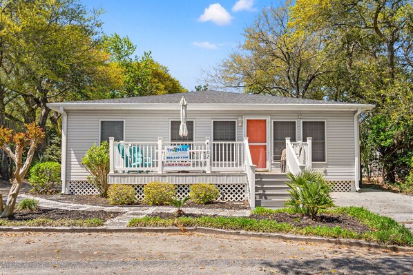 A single-story house with a porch, a mailbox, and a sign advertising a Palm in the Sand. - Cozy, pet-friendly home - blocks from the ocean - close to shops, eateries, entertainment (North Myrtle Beach)