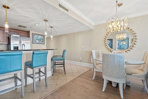 A modern kitchen with a bar area, dining chairs, and a chandelier.