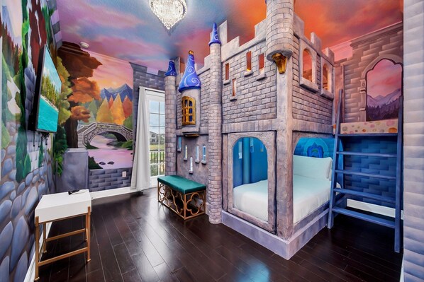 A castle-themed room with a bed, a bench, and a small table.