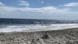 Una playa con arena y el océano al fondo.