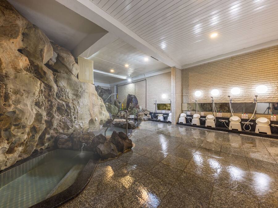 A hot spring area with a stone wall, a hot tub, and multiple toilet facilities.