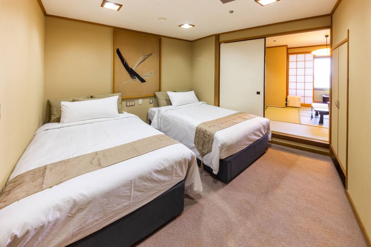 A hotel room with two beds, a large mirror, and a view of the outside.