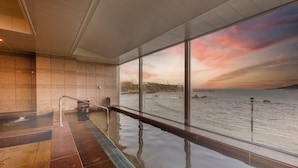 Une piscine intérieure moderne offrant une vue sur la mer au coucher du soleil.