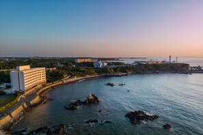 A coastal hotel with a view of the sea and a lighthouse in the distance.