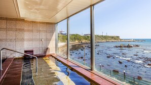 Un espace spa doté d’une grande fenêtre donnant sur une côte rocheuse.