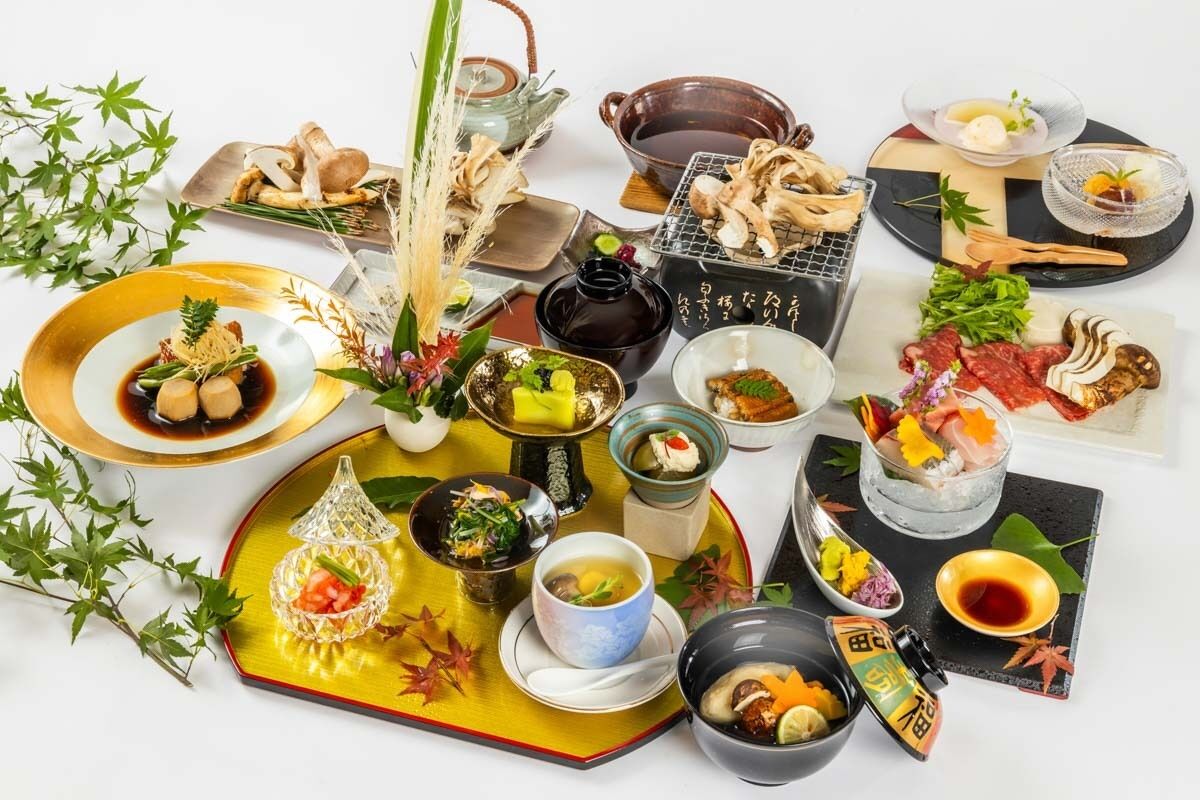 Variedad de platos y bebidas japonesas sobre una mesa, incluyendo sushi, sashimi y una tetera.