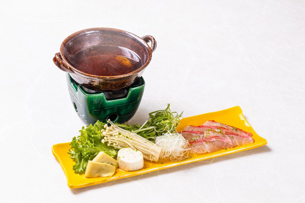Een maaltijd met sashimi, groenten en een hete pot.