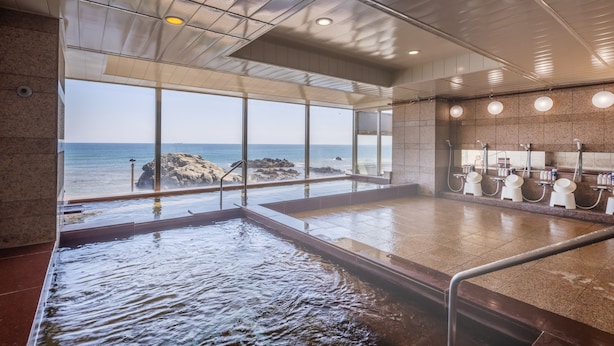Un espace spa doté d’une grande fenêtre donnant sur la mer, d’un élément décoratif aquatique et d’une rangée de lavabos.