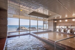 A spa area with a large window overlooking the sea, a water feature, and a row of sinks.