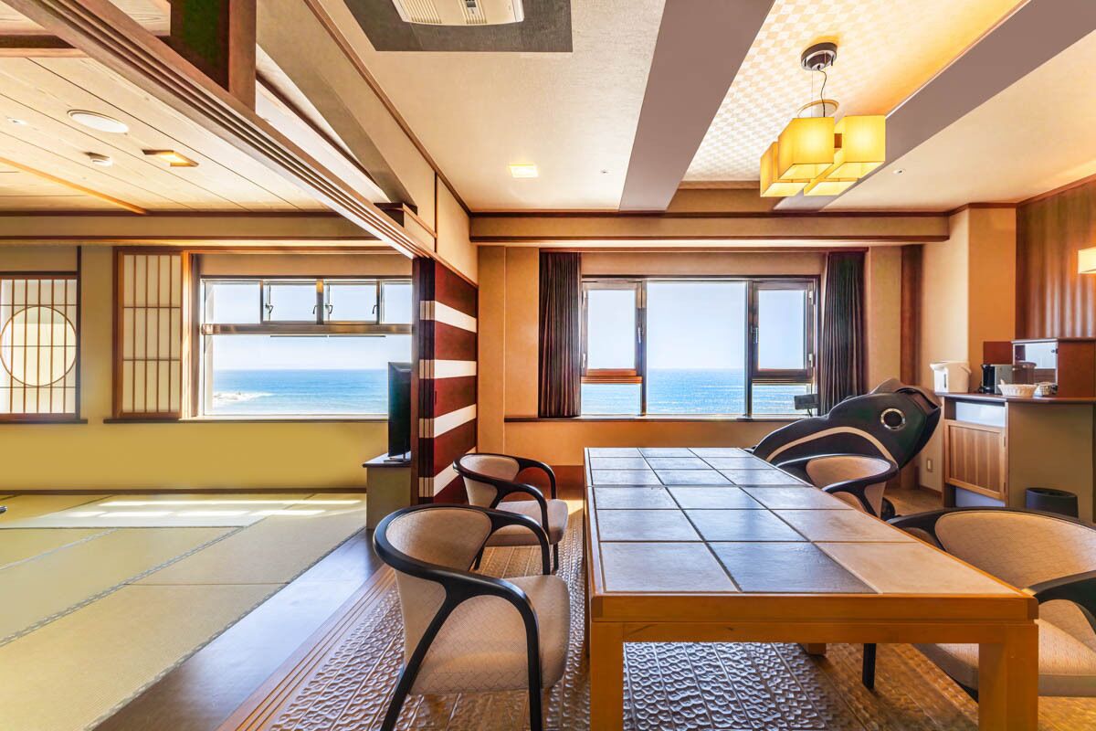 Una habitación con un ventanal grande que ofrece vista al mar, una mesa de madera y varias sillas.