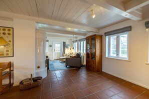 Ein geräumiges Wohnzimmer mit Kamin, einem Essbereich und einer durch einen offenen Durchgang einsehbaren Küche.