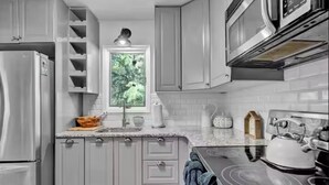 A kitchen with white cabinets, a refrigerator, a stove, and a window with a view of greenery. - The Easy St Chalet in Albrightsville (Albrightsville)