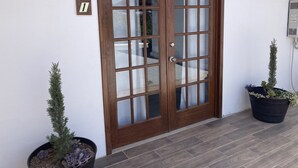 A wooden double door with glass panels, a potted plant beside it, and a small sign with the number 1 on the wall. - Casa Ciprés (Valle de Guadalupe)