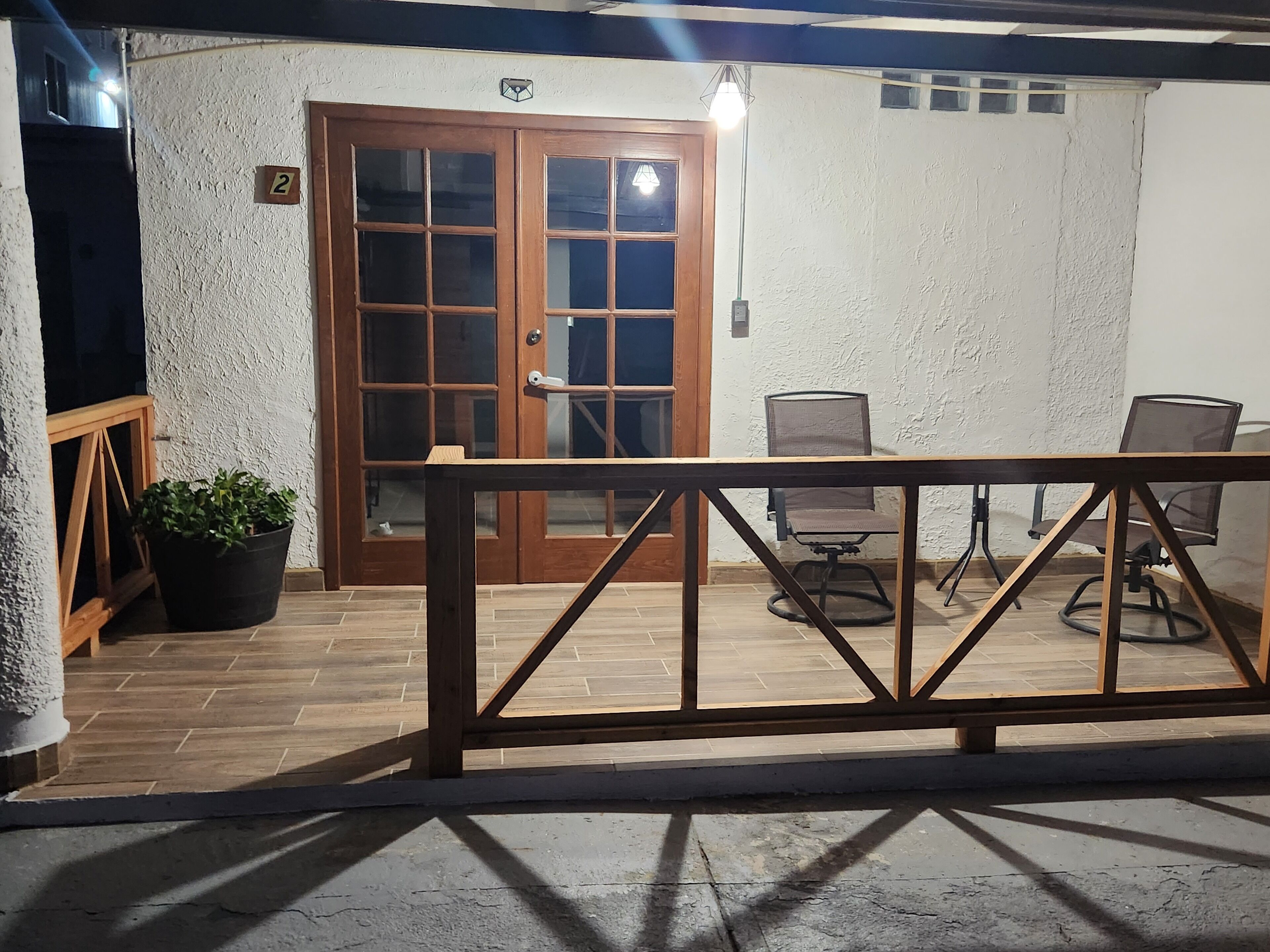 A patio area with a wooden railing, a door with glass panels, and two office chairs.