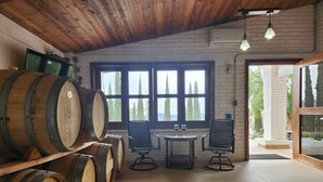 A rustic interior with wooden barrels, a brick wall, and large windows. - Casa Ciprés (Valle de Guadalupe)
