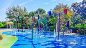 Un área de juegos con agua, estructuras coloridas y una zona de estar.