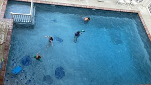 Una piscina rectangular con borde de azulejos y una escalera blanca en un lateral.
