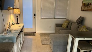Un espacio habitable compacto con kitchenette, comedor y sofá con cojines.