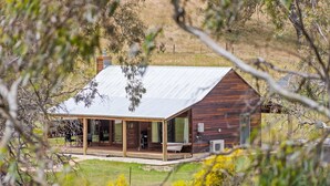 Una casa moderna amb un gran porxo, una banyera i una zona d'estar exterior coberta.