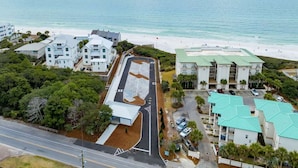 Vue aérienne d’un hôtel situé sur la côte, composé de plusieurs bâtiments, avec un parking et une plage en arrière-plan.