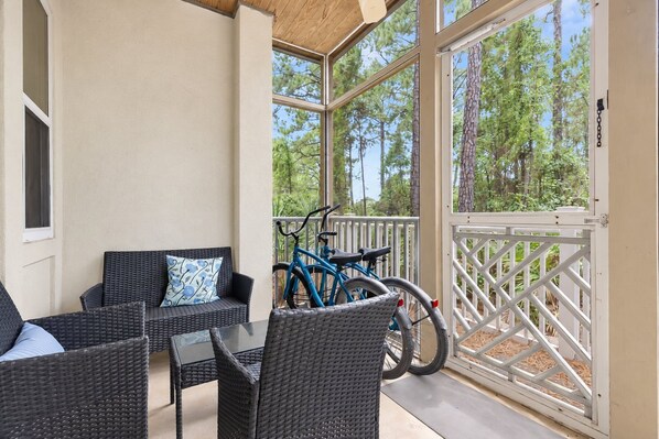 A covered outdoor seating area with wicker furniture and a bicycle. - Happy Days - 3BR/2BA Seagrove Highlands Condo - Sleeps 7 - Community Pool - 4 Bikes (Santa Rosa Beach)