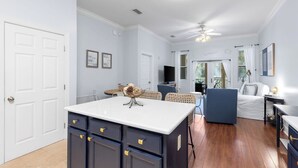 Un vaste espace de vie comprenant un îlot de cuisine, une table à manger et un coin salon avec un canapé et des fauteuils.