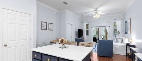 A spacious living area with a kitchen island, a dining table, and a seating area with a sofa and chairs.