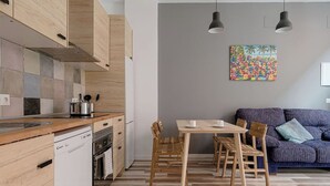 Eine moderne Küche mit Holzschränken, einem Geschirrspüler und einem Essbereich mit Tisch und Stühlen.