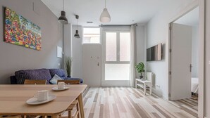 Ein modernes Wohnzimmer mit Esstisch, Sofa und einem farbenfrohen, abstrakten Gemälde an der Wand.