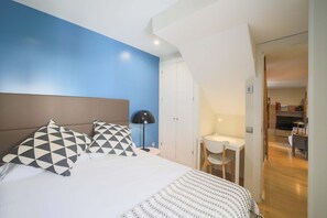 Un dormitorio con cama, escritorio y silla.
